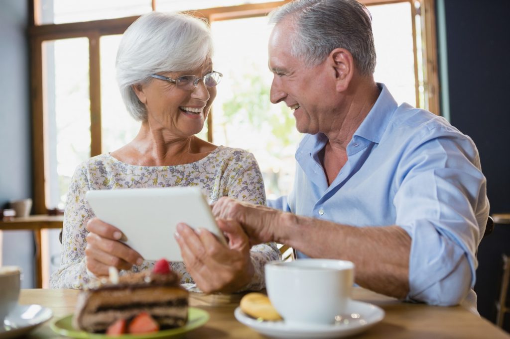 Happy senior couple using a tablet to explore Medicare Agents to get them advice in their area.