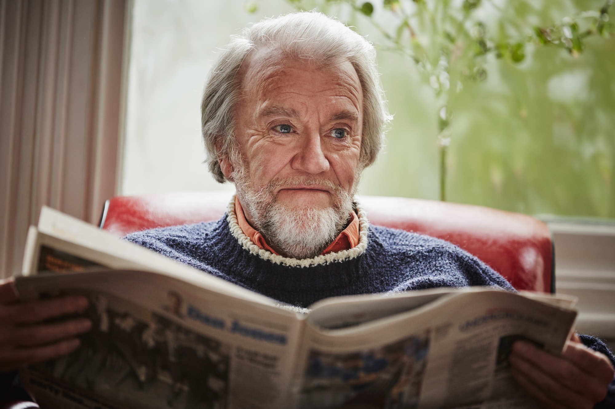 Senior man reading newspaper article about plan F medicare.