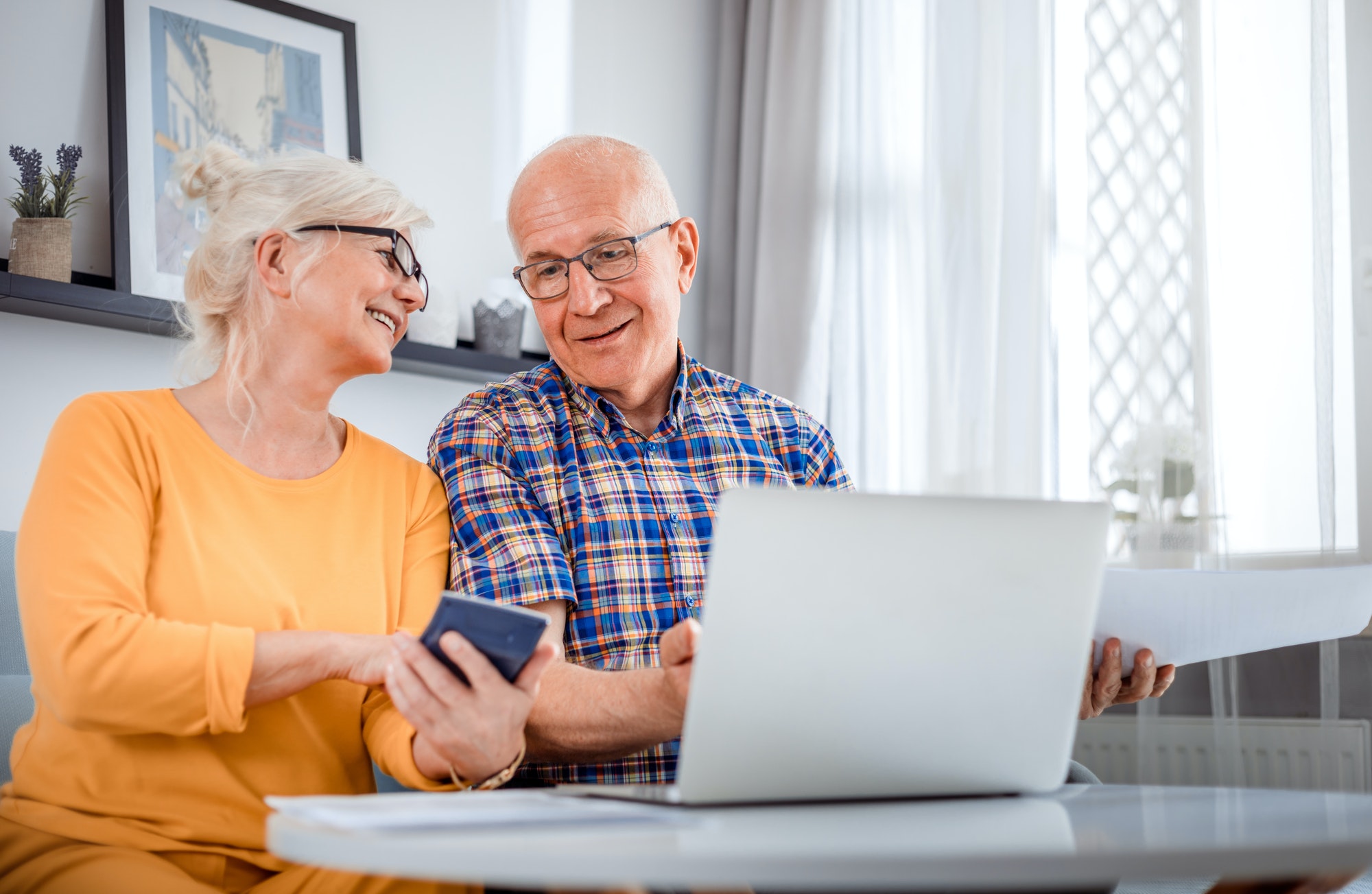 Senior couple checking cost of plan G using laptop at home